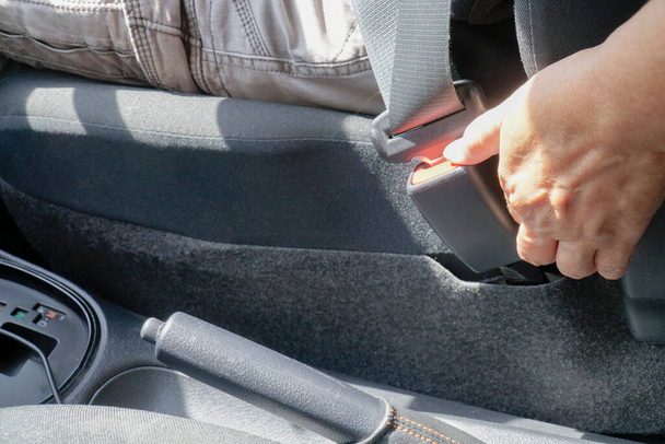 Zblízka žena rozepne bezpečnostní pás auta s rukou v autě. Koncept bezpečnosti a dopravy - Fotografie, Obrázek