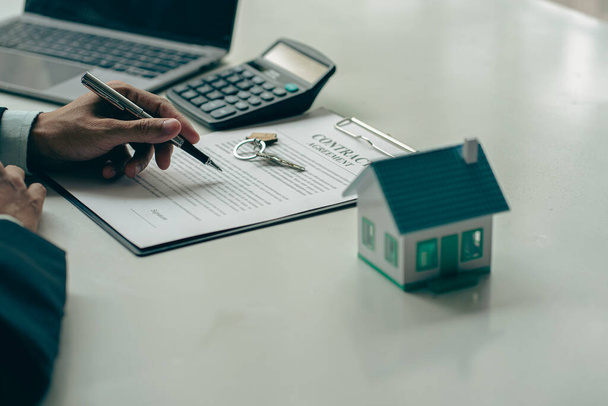 Immobilienmakler, Hausverkäufer, arbeiten an der Dokumentation von Eigenheimkrediten an Kunden und abgeschlossenen Eigenheimverträgen. am Schreibtisch im Büro - Foto, Bild