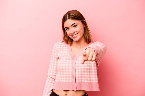 Young caucasian woman isolated on pink background cheerful smiles pointing to front. - 写真・画像