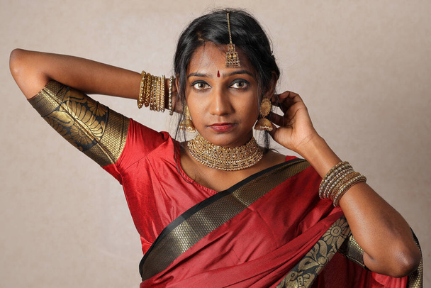Indická žena na sobě červená oranžová saree šperky choker set náhrdelník jhumka náušnice maang tikka pas řetěz stojan póza pohled vidět úsměv nálada výraz  - Fotografie, Obrázek