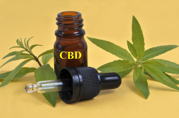 Konzept der CBD-Dosierung Flasche und Cannabisblätter auf gelbem Hintergrund - Foto, Bild