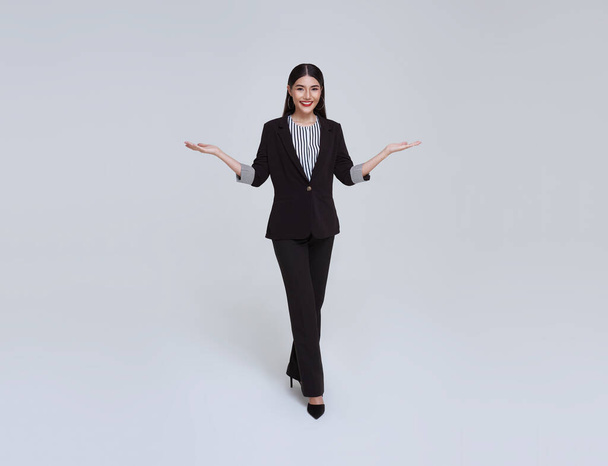 Sonriente mujer de negocios asiática segura con gesto de introducir aislado sobre fondo gris. - Foto, imagen