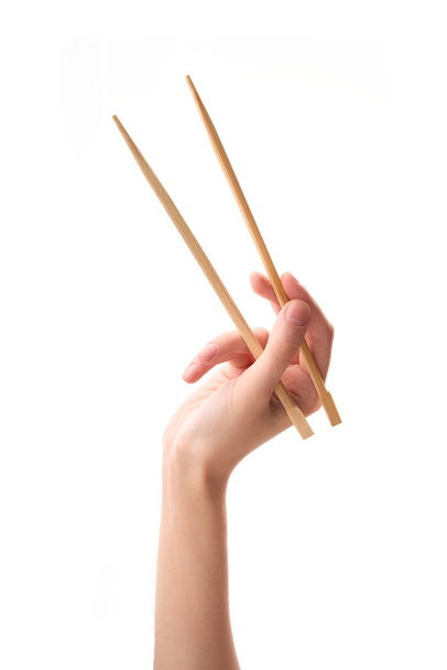 female hand holds Wooden chopsticks isolated on white background. - Fotó, kép