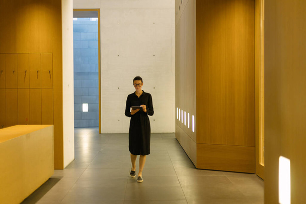 Kobieta korzystająca z tabletu w minimalistycznej przestrzeni biurowej - Zdjęcie, obraz