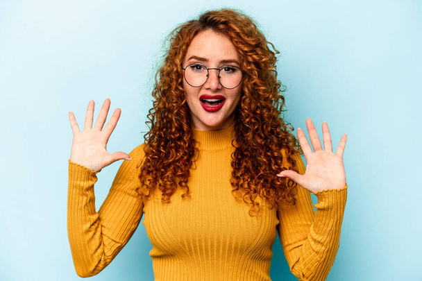 Young ginger caucasian woman isolated on blue background receiving a pleasant surprise, excited and raising hands. - Photo, Image