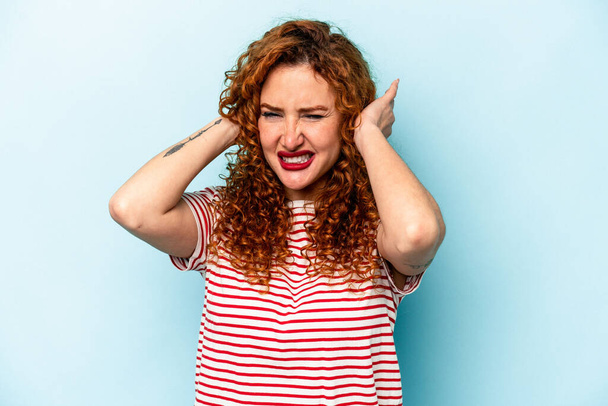 Young ginger caucasian woman isolated on blue background covering ears with hands. - Foto, Imagen