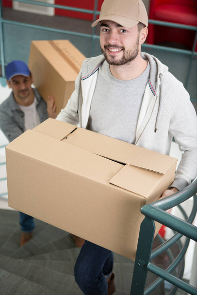 two men carrying boxes up a flight of stairs - Foto, Bild