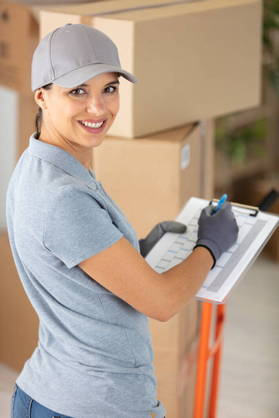 female courier delivering packages holding clipboard - Foto, imagen