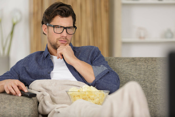 male with tv remote control and popcorns - Фото, изображение