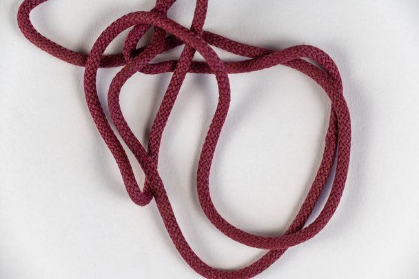 A tangled red rope against a neutral background. Round rope without knots. Close-up. Selective focus. - Foto, immagini
