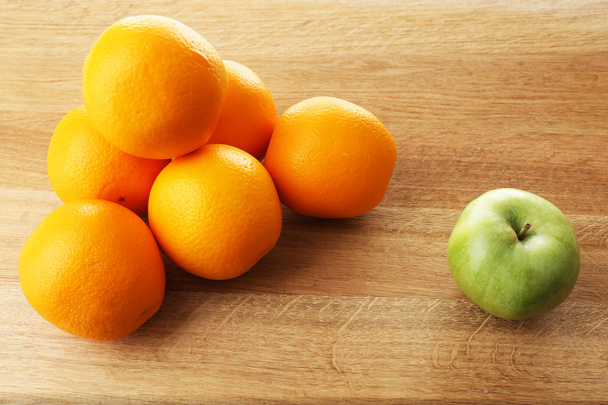 Juicy oranges and green apple on wooden table - Fotografie, Obrázek