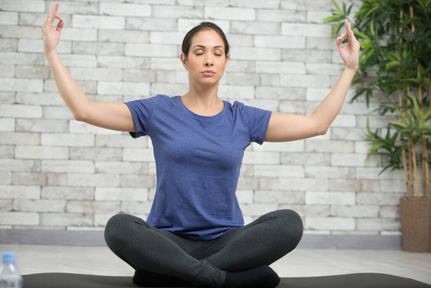 meditative woman in lotus position with arms raised - Foto, afbeelding