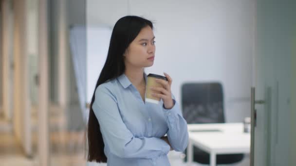 Style de vie au bureau. Jeune femme asiatique sereine menager debout au couloir de bureau avec café à emporter, passer son temps de pause seule, regarder de côté, ralentir - Séquence, vidéo