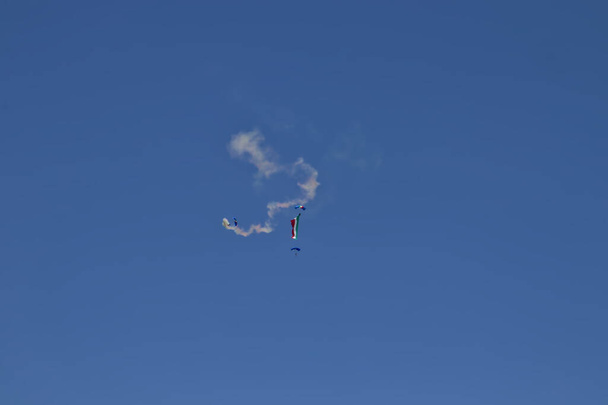 Un paracaidista militar lanzado desde un helicóptero desenrolla la bandera italiana, en un día de la república italiana. - Foto, imagen