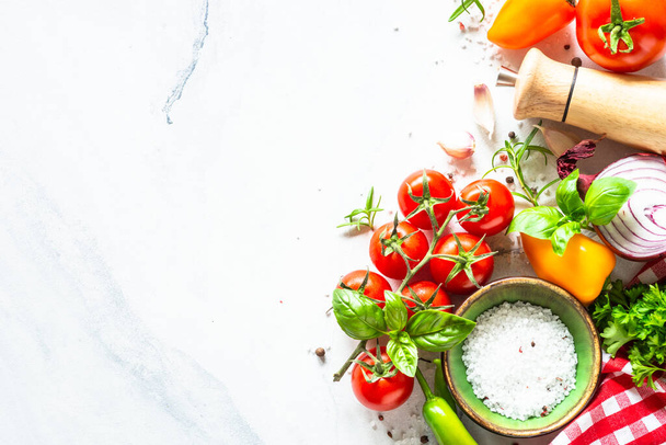 Voedselachtergrond op witte marmeren tafel met groenten, kruiden en specerijen. Bovenaanzicht met kopieerruimte. - Foto, afbeelding