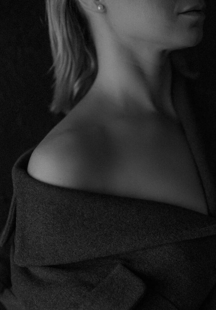 woman in a coat close-up neck chest model healthy skin inside a dark roo - Foto, imagen