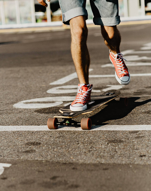 Young man in red sneakers rides a skateboard. . Free relaxing trendy skateboard concept. hipster style - Φωτογραφία, εικόνα