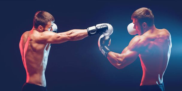 Two boxers boxing on dark background with copy space. Sport concept. - Foto, Imagen