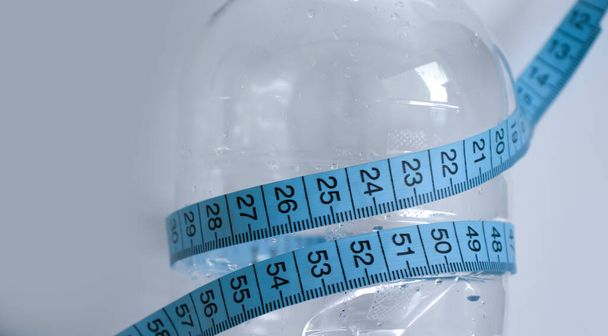 Пляшка водяного сантиметрової стрічки на світлому фоні
 - Фото, зображення