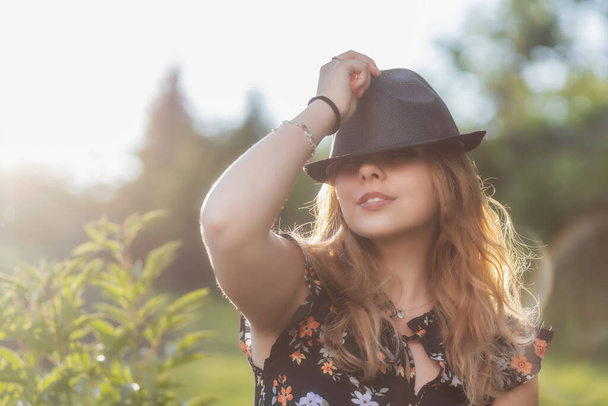 Portrait of posing attractive  young woman in black  straw hat in outside. Horizontally.  - 写真・画像