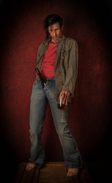 Junkie άνθρωπος με μαύρα μαλλιά και μπουκάλι με κοινό κοντά vintage κόκκινο τοίχο - Φωτογραφία, εικόνα
