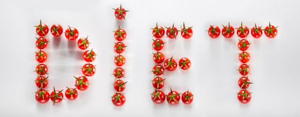 Wit bord met daarop cherry tomaten uiteengezet het woord dieet - Foto, afbeelding