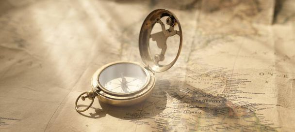 Retro style antique golden compass (sundial) and old nautical chart close-up. Vintage still life. Sailing accessories. Wanderlust, travel and navigation theme. Graphic resources, copy space - 写真・画像
