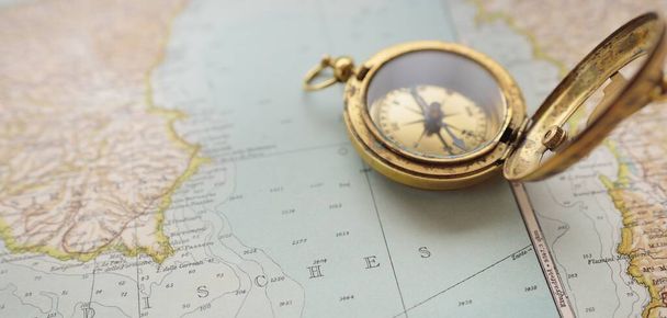 Retro style antique golden compass (sundial) and old nautical chart close-up. Vintage still life. Sailing accessories. Wanderlust, travel and navigation theme. Graphic resources, copy space - 写真・画像