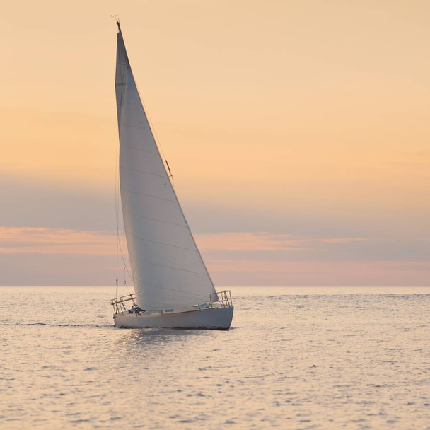Bílá šalupa manipulované jachty plachtění v Baltském moři při západu slunce. Jasná obloha po bouři, zlaté sluneční světlo. Doprava, cestování, plavba, sport, rekreace, volný čas, závodní, regata - Fotografie, Obrázek