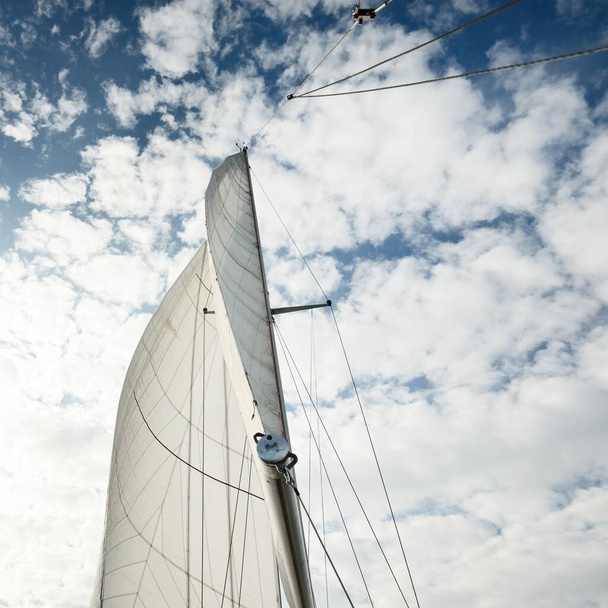 Λευκό ιστιοφόρο ιστιοπλοϊκό σκάφος στη Βαλτική θάλασσα το ηλιοβασίλεμα. Θέα από το πιλοτήριο στο κατάρτι και πανιά. Δραματικός ουρανός. Μεταφορά, ταξίδια, κρουαζιέρα, αθλητισμός, αναψυχή, δραστηριότητες αναψυχής, regatta - Φωτογραφία, εικόνα