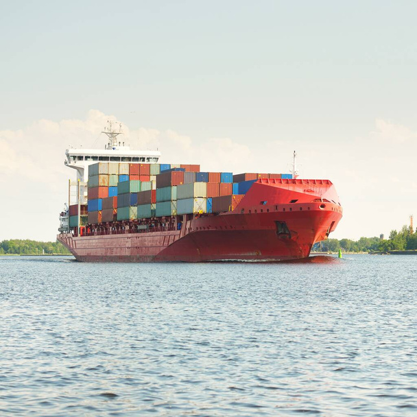 Контейнерный корабль (168 метров в длину) покидает терминал порта на закате. Балтийское море. Транспорт, логистика, глобальные коммуникации, международные перевозки, экономика, бизнес, промышленность - Фото, изображение