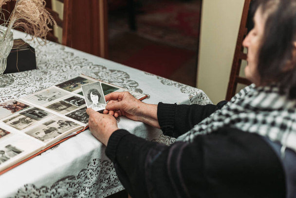 CIRCA 1970: Las manos de la anciana sosteniendo la foto vintage, en blanco y negro del yo joven. Concepto del paso del tiempo - Foto, imagen