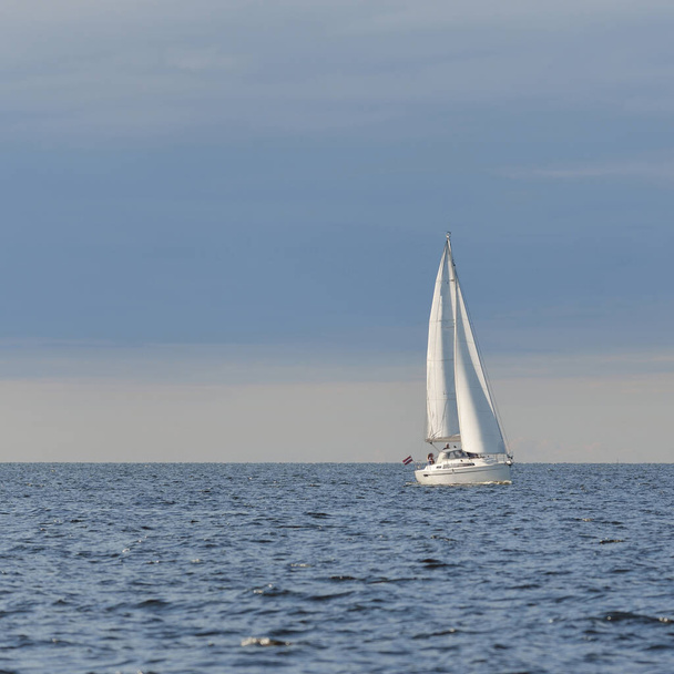 Шлюп оборудовал яхту, плывущую в Балтийском море. Закат. Драматическое небо после шторма, мягкий солнечный свет. Отдых, путешествия, круиз, гонки на яхтах, спорт, отдых, отдых, образ жизни, семья - Фото, изображение