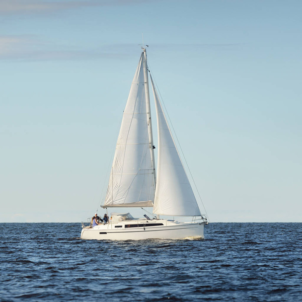 Fehér sloop manipulált jacht vitorlázás a Balti-tengeren naplementekor. Tiszta ég a vihar után, lágy napfény. Közlekedés, utazás, sétahajózás, sport, rekreáció, szabadidős tevékenység, verseny, regatta - Fotó, kép