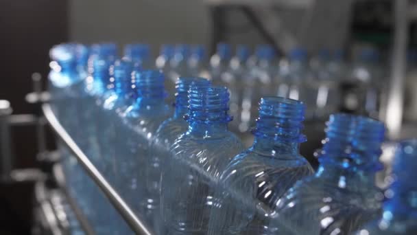 Le bottiglie di plastica blu vuote vengono spostate su un nastro trasportatore. Impianto di produzione di acqua minerale. - Filmati, video