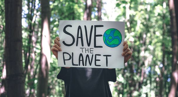 Cartel en el llamado a salvar el planeta en manos femeninas en el bosque, el concepto de cuidar la naturaleza, la limpieza, el reciclaje y la ecología. - Foto, imagen