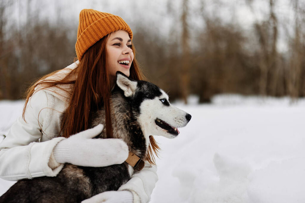 Kış tatilinde köpeğiyle birlikte dışarıda bir tarlada yürüyüş yapan neşeli bir kadın. Yüksek kalite fotoğraf - Fotoğraf, Görsel