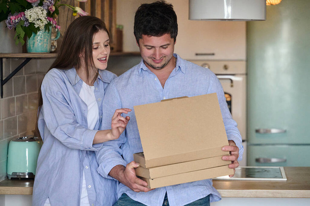 young beautiful couple with pizza boxes in hands in the kitchen. Fast delivery concept - Foto, immagini