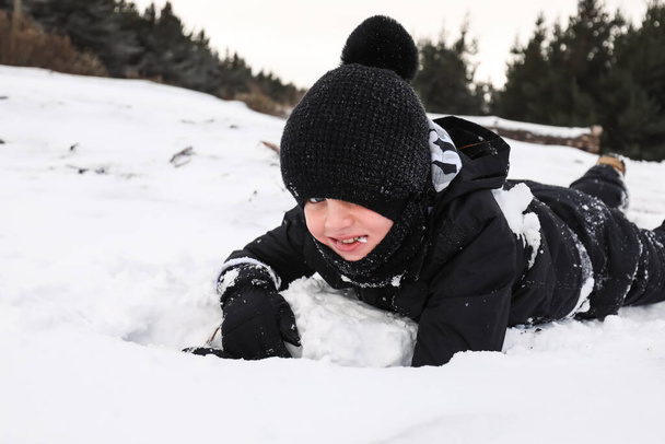 Happy boy playing in snowy winter wonderland eating snow - Photo, Image