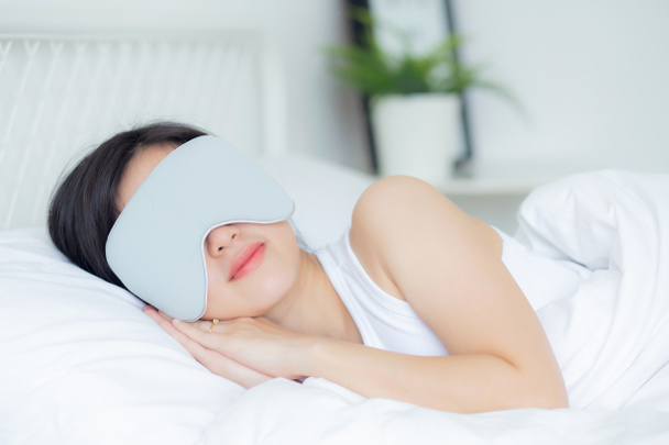 Beautiful young asian woman wearing cover eye and sleeping on bed with head on pillow comfort and happiness in the bedroom at home, girl with relax and leisure for wellness, lifestyles concept. - Fotoğraf, Görsel