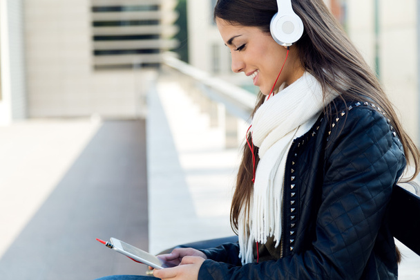 Beautiful girl listening to music in city.  - Foto, afbeelding