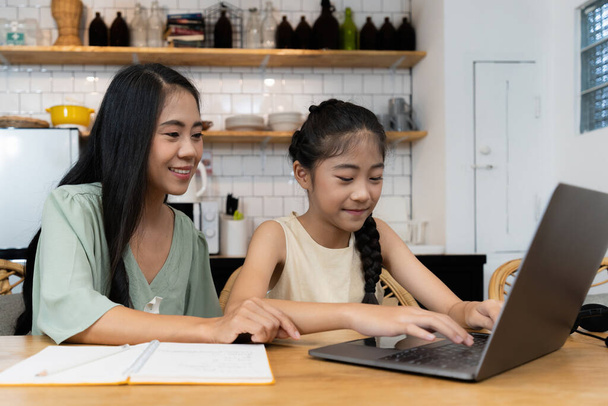 Koncepcja rodziny i szkoły domowej. Azji matka uczyć jej córka za pomocą aplikacji na laptopie w domu - Zdjęcie, obraz