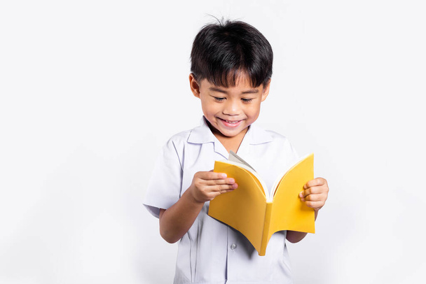 Asian toddler smile happy wearing student thai uniform red pants standing holding and reading a book in studio shot isolated on white background, Portrait little children boy preschool, Back to school - Photo, Image