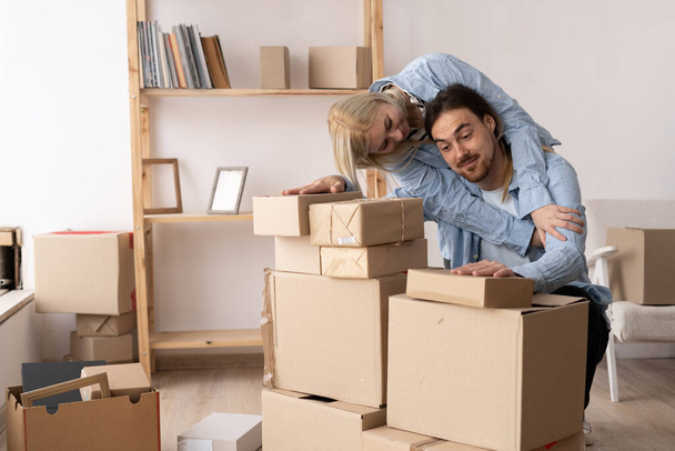 Couple emménageant dans la maison, homme et femme parmi les boîtes dans un nouvel appartement, le jour du déménagement. Concept d'achat immobilier ou immobilier - Photo, image