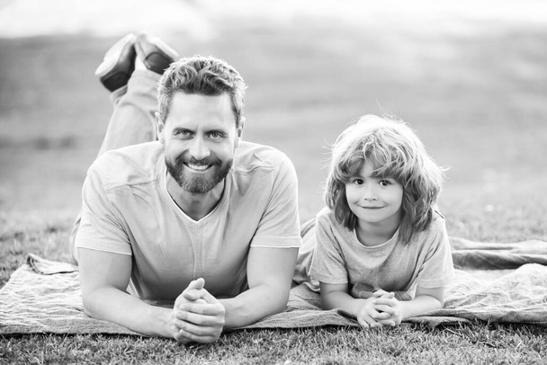 Father and son relaxing on nature in park. Concept of children and parents, happy family - 写真・画像