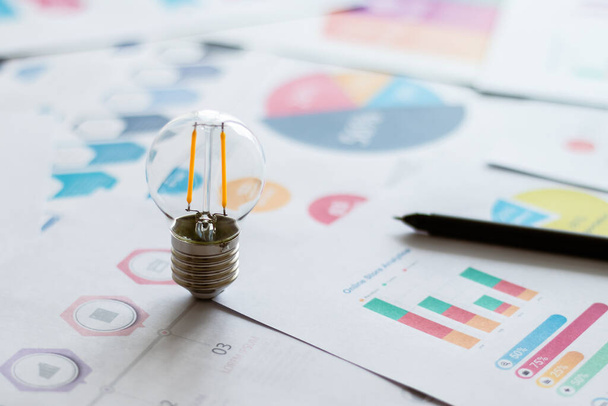 Light bulb with graph information document. Businessperson analysis data for corporate or entrepreneur planning for small business growth or success. Business and financial idea concept - Photo, Image