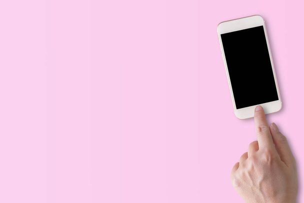 Κορυφαία εικόνα της γυναίκας χέρι χρησιμοποιώντας έξυπνο τηλέφωνο με άδεια οθόνη σε ροζ φόντο. Επιχειρηματικό μάρκετινγκ για την προώθηση banner ιδέες έννοια. - Φωτογραφία, εικόνα
