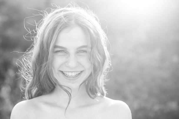 Beautiful smiling teenage girl in blue blouse, against green of summer park. Beauty joyful teen girl on sunset enjoying nature and laughing on summer field - Φωτογραφία, εικόνα