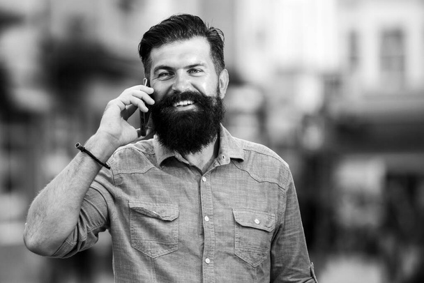 Smiling man call phone and smile outdoor city street. Happy businessman in casual blue shirt talking on mobile - Photo, Image