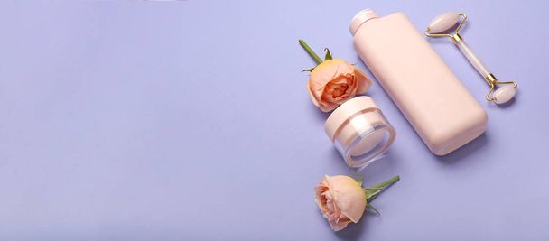 Prodotti cosmetici, strumento di massaggio facciale e fiori di rosa su sfondo lilla con spazio per il testo - Foto, immagini
